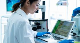 Woman in a white lab coat working on a computer in a research lab