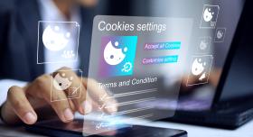user touching cell phone that is laid flat on a table. A projection of their screen is visible in the air showing a cookies setting window with options to opt out or accept.