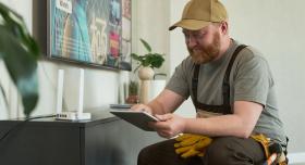 Audio Visual Installation Technician typing on tablet device while repairing Television