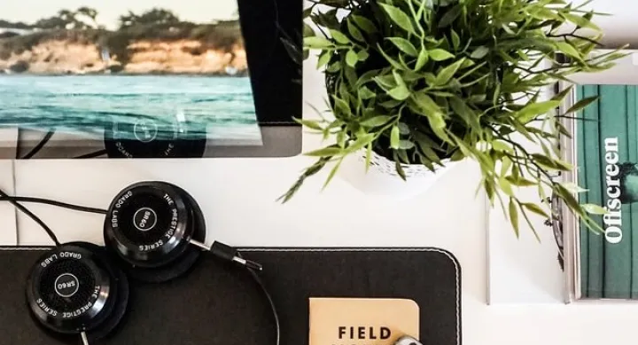 phone, book, headphones, and computer on clean desk