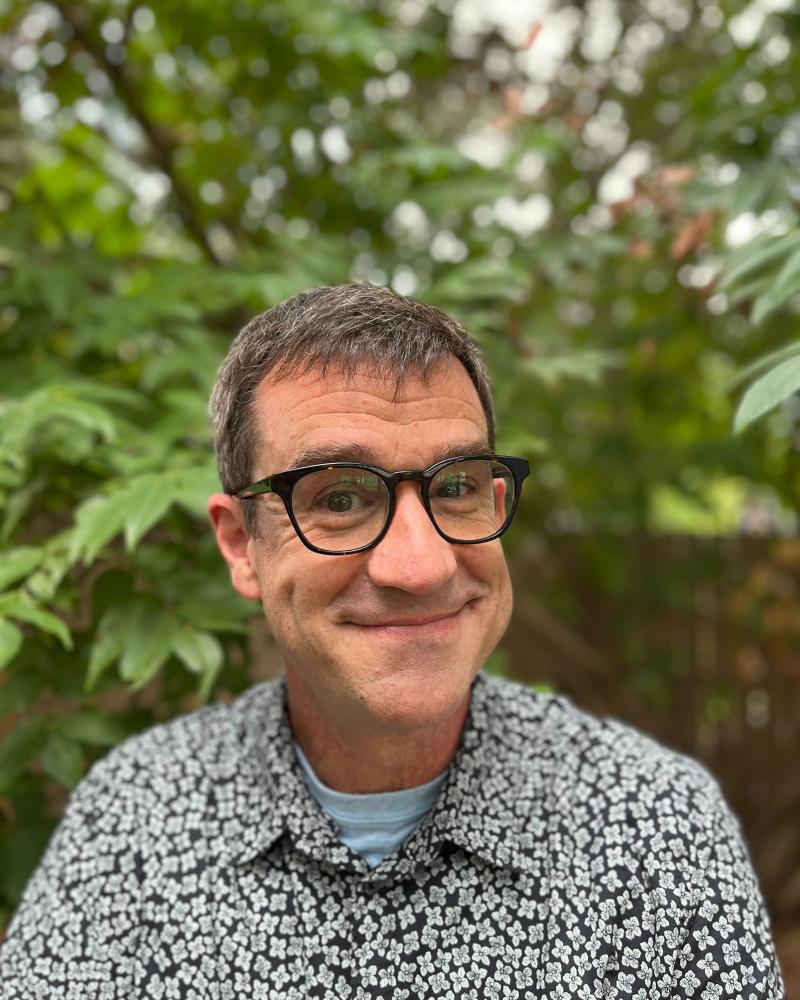 smiling man in front of trees